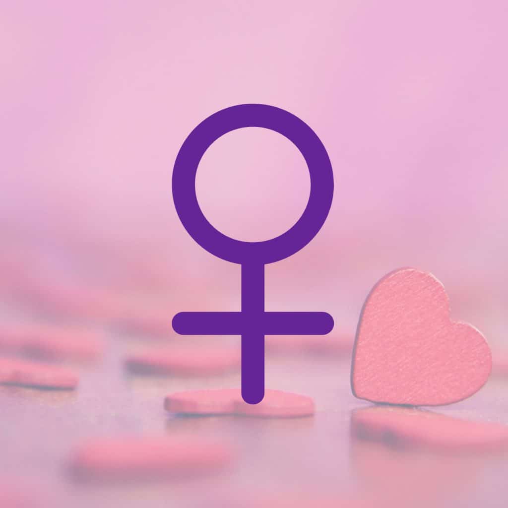 Fond rose avec des petits coeurs rouges en carton, et en premier plan le symbole de la planète Vénus, planète de l'amour