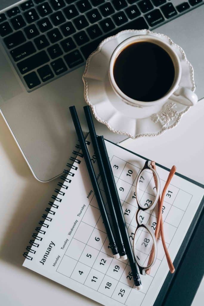un ordinateur, un café, des crayons, des lunettes et un agenda
